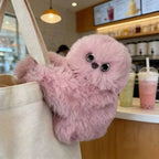 Solis Bag Charm — pink, peering out of a canvas tote