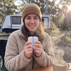 Solis Ember twin hand warmers cupped in both hands at an outdoor table on a cold morning