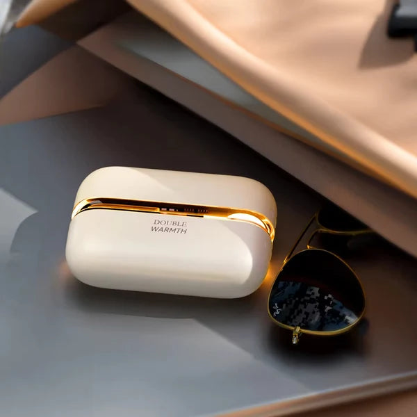 Solis Ember twin hand warmers closed, resting on a tray beside sunglasses and a silk scarf