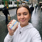 Solis Ember twin hand warmers held up on a wet city street, the seam lit blue