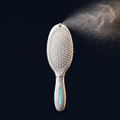 Solis Mist Hydrating Hair Brush — brush standing upright with a fine mist plume catching gold rim-light