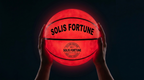 Solis Arc LED Basketball — held overhead in the dark, both LEDs lit