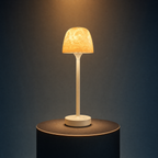The Solis Vesta table lamp on a lit black podium, warm amber light through its textured dome shade