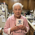 Solis Beacon — elderly woman in her kitchen holding the SOS bracelet box