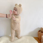 A baby in the tan Solis Bear Cub Romper and bonnet