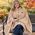 Solis Ember Heated Wearable Blanket in beige worn on a city bench with a coffee