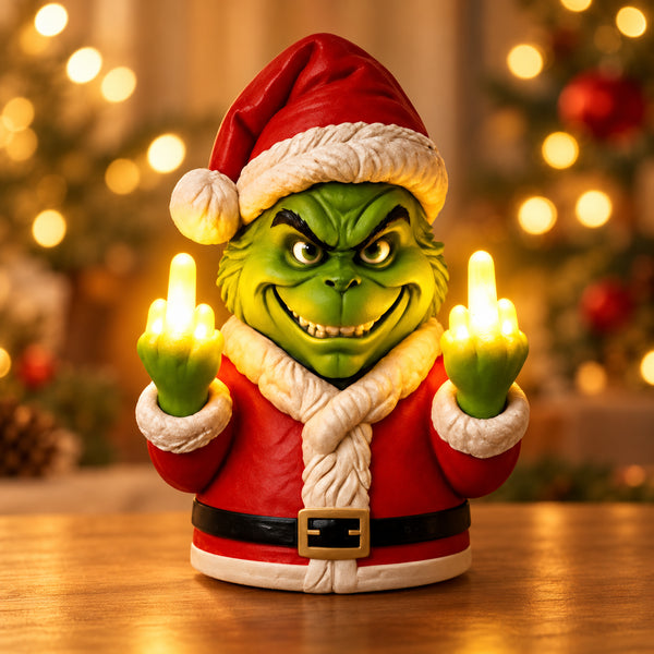 Solis Naughty Glow - Green Monster (Grinch Style) lamp in a red Santa suit with two glowing middle fingers, on a warm wooden tabletop